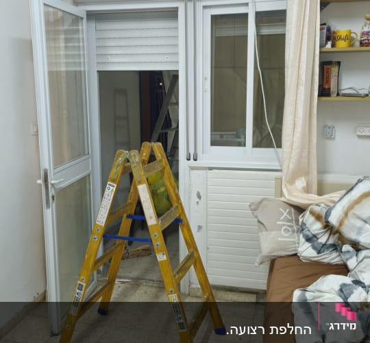 סולם עץ ותרסיס שימון במהלך תיקון חלון הזזה ותריס גלילה